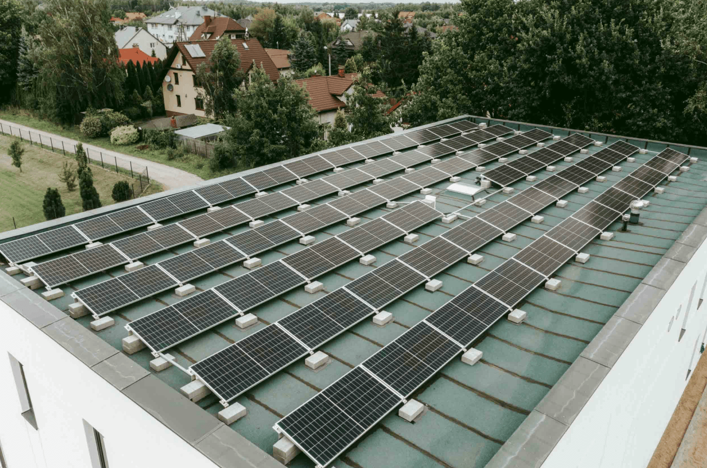 Instalacja fotowoltaiczna na płaskim dachu magazynu, panele w rzędach z balastem